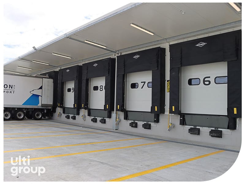 Four loading docks with black seals and white sectional doors numbered 06 to 09.